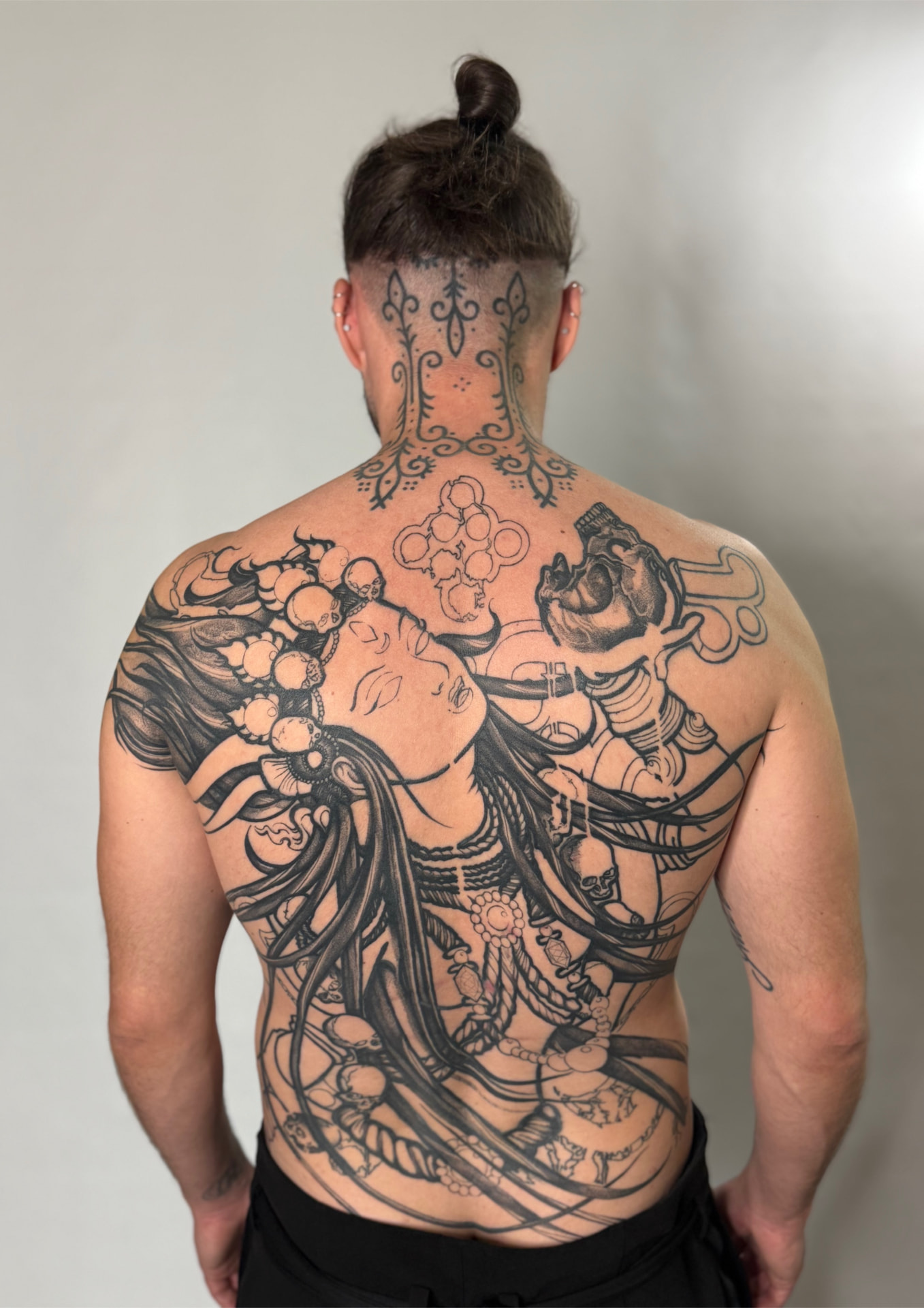 Large illustrative blackwork back piece with skulls and flowing hair