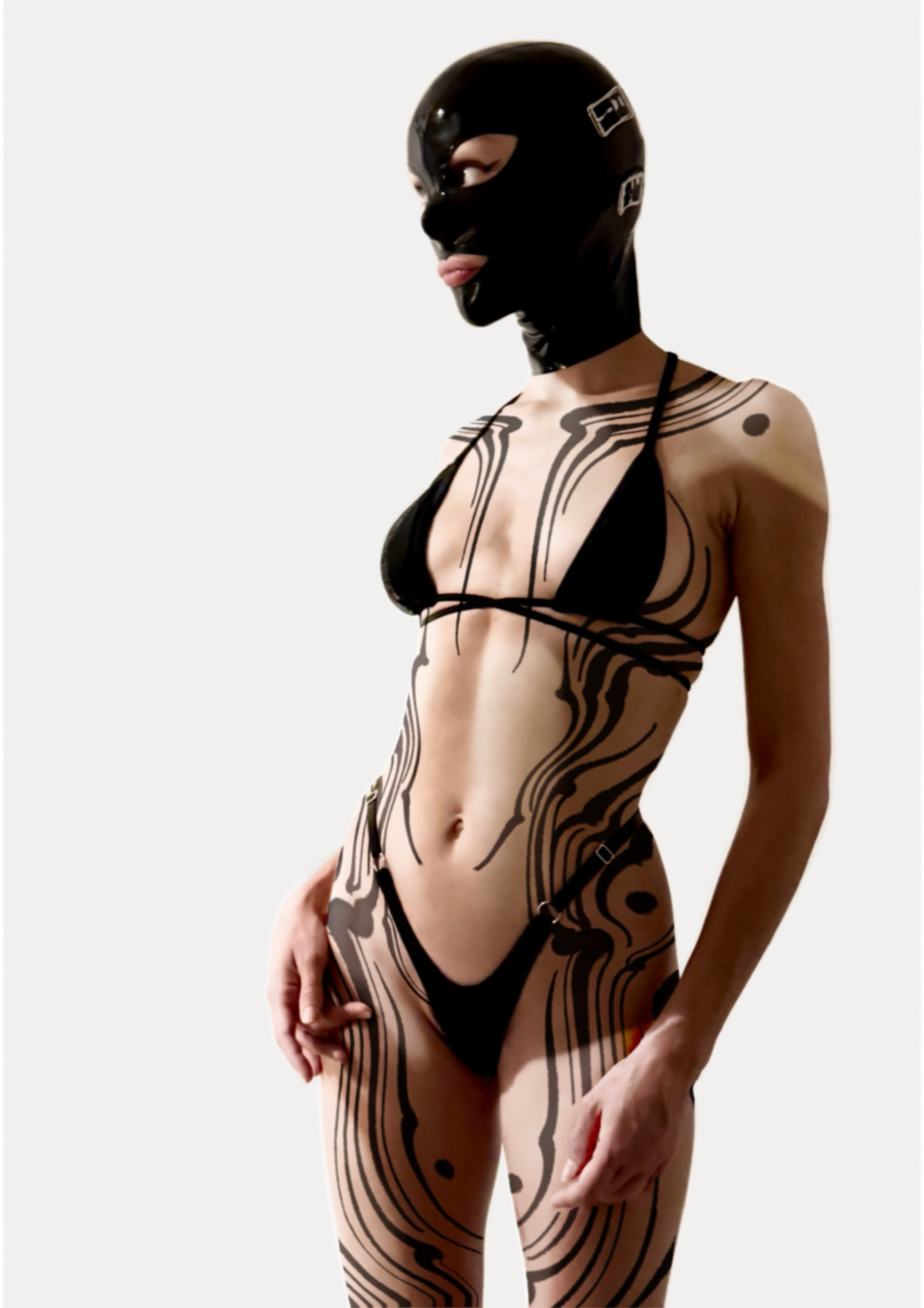 Masked figure in black lingerie with bold blackwork linear tattoos